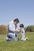 Hispanic father and son playing soccer outdoors
