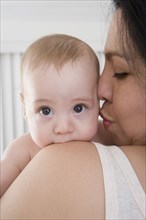Mother kissing Hispanic baby boy's cheek
