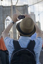 Hispanic man photographing Brooklyn Bridge