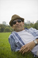 Portrait of Hispanic man laying in grass at park