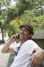 Portrait of smiling Hispanic man talking on cell phone in park