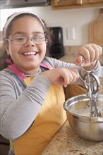 Portrait of smiling Hispanic girl baking in kitchen