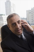 Portrait of Hispanic businessman talking on cell phone in office