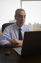 Hispanic businessman using laptop in office
