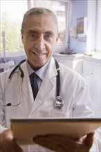 Close up portrait of smiling Hispanic doctor with digital tablet
