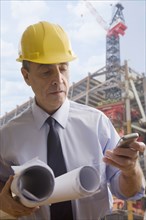 Hispanic architect using cell phone at construction site