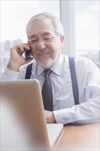 Hispanic businessman talking on cell phone at desk