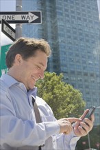 Hispanic businessman using cell phone on city street