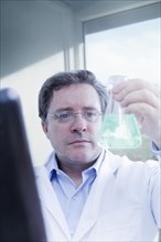 Hispanic scientist examining beaker in lab