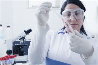 Hispanic scientist pipetting blood sample in laboratory