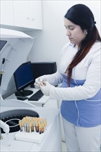 Hispanic scientist testing blood sample in laboratory centrifuge