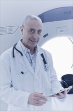 Hispanic doctor using digital tablet near MRI scanner