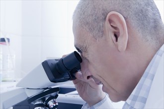Hispanic scientist using microscope in lab