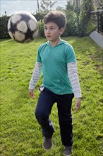 Hispanic boy juggling soccer ball in backyard