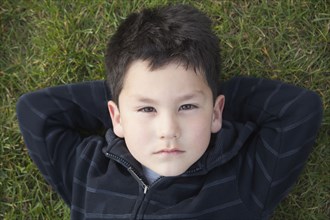 Hispanic boy laying in grass