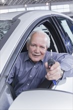 Hispanic man holding keys to new car