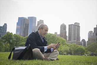 Hispanic businessman using cell phone in urban park