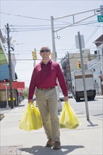 Hispanic man carrying shopping bags on city sidewalk