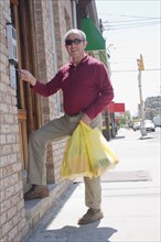 Hispanic man with shopping bags unlocking front door