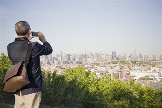 Hispanic man photographing New York cityscape