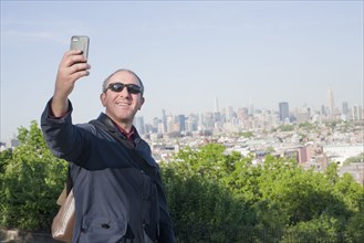 Hispanic man taking selfie with New York cityscape