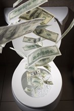 Dollar bills falling into toilet