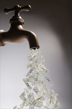 Dollar bills pouring out of faucet