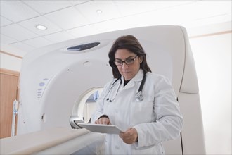 Hispanic doctor using digital tablet in MRI room