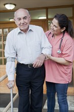Hispanic nurse helping patient walk with crutch