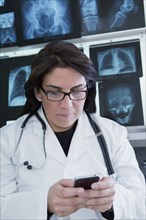 Hispanic doctor using cell phone in hospital