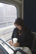 Hispanic woman using cell phone on train