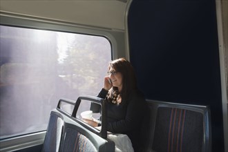 Hispanic woman talking on cell phone on train