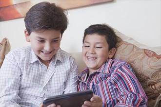 Hispanic brothers using digital tablet
