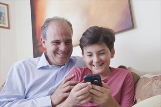 Hispanic father and son texting on cell phone