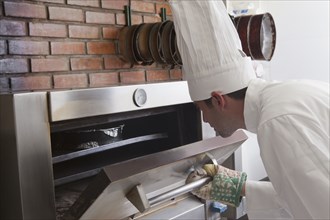 Hispanic chef checking oven