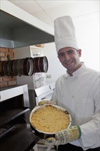 Hispanic chef holding cheesecake near oven