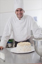 Smiling Hispanic chef posing with cake