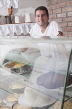 Hispanic baker posing behind display case