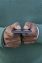 Hands of Hispanic man texting on cell phone