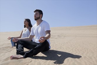 Hispanic couple meditating at beach