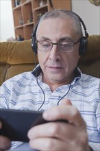 Curious Hispanic man listening to cell phone with headphones