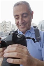 Hispanic man examining photograph on digital camera