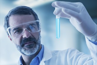 Hispanic researcher holding vial of blue liquid