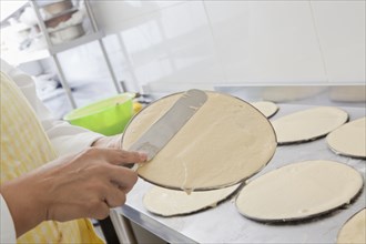 Hispanic woman spreading batter on pan