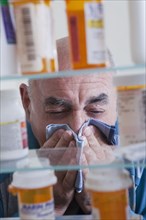 Hispanic man wiping nose near medicine cabinet
