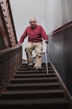 Hispanic man with cane descending staircase