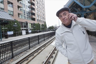 Hispanic man waiting at train station talking on cell phone