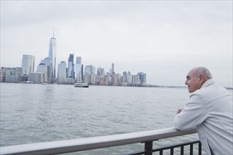 Hispanic man leaning on railing admiring scenic view of city