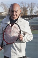 Smiling Hispanic man holding tennis racket