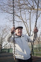 Carefree Hispanic man on swing in park